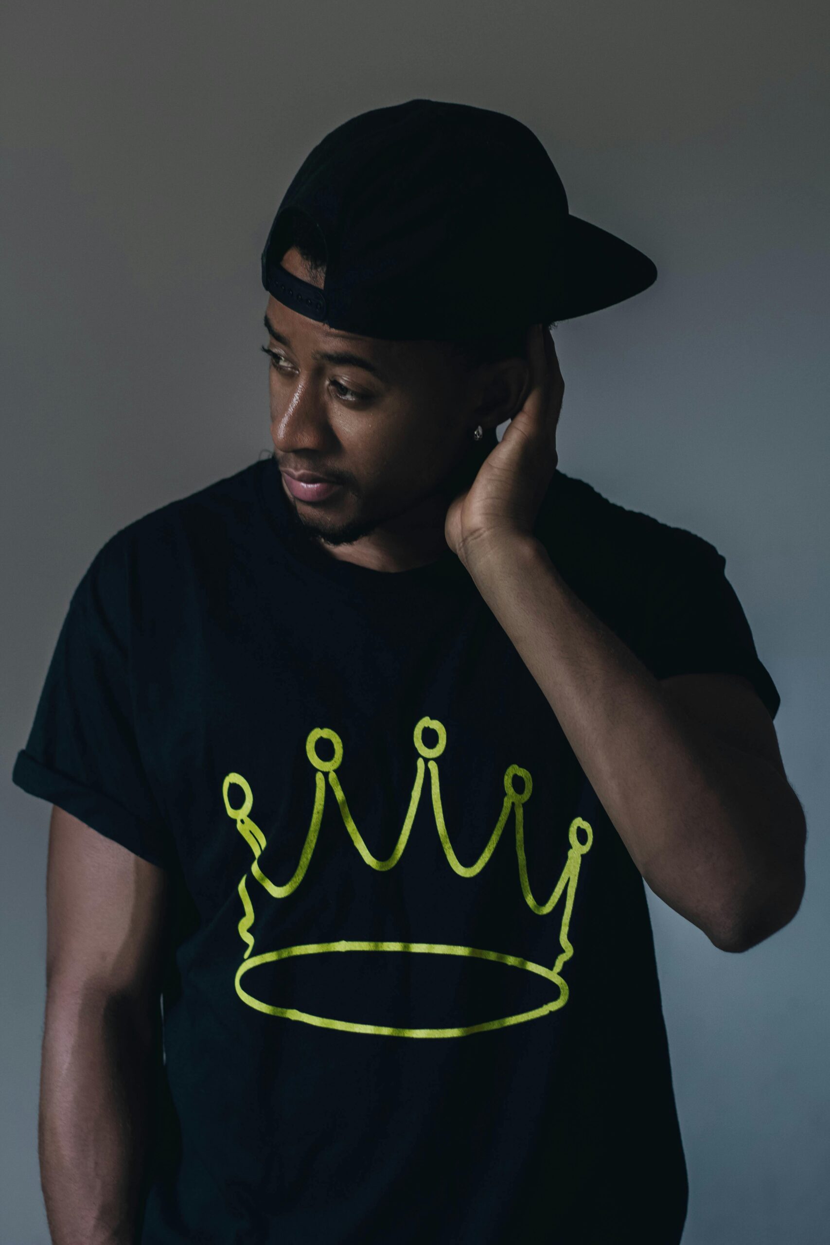 Portrait of a fashionable young man in a studio with a crown design on his shirt, exuding confidence.