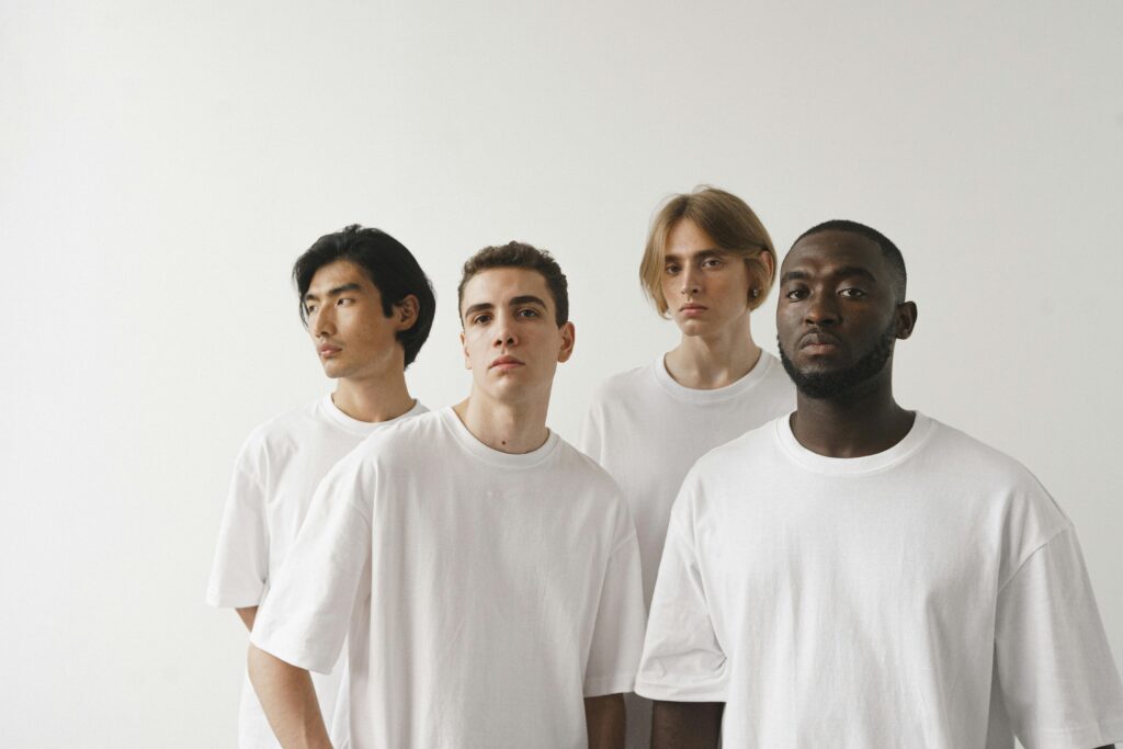 Studio portrait of diverse group of serious men in white shirts on a plain background.